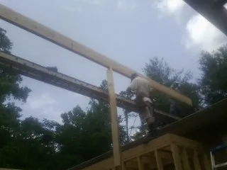 Carpenter setting a ridge beam over a new addition frame — Ice Dam Removal by Roofing Brothers in Harpswell