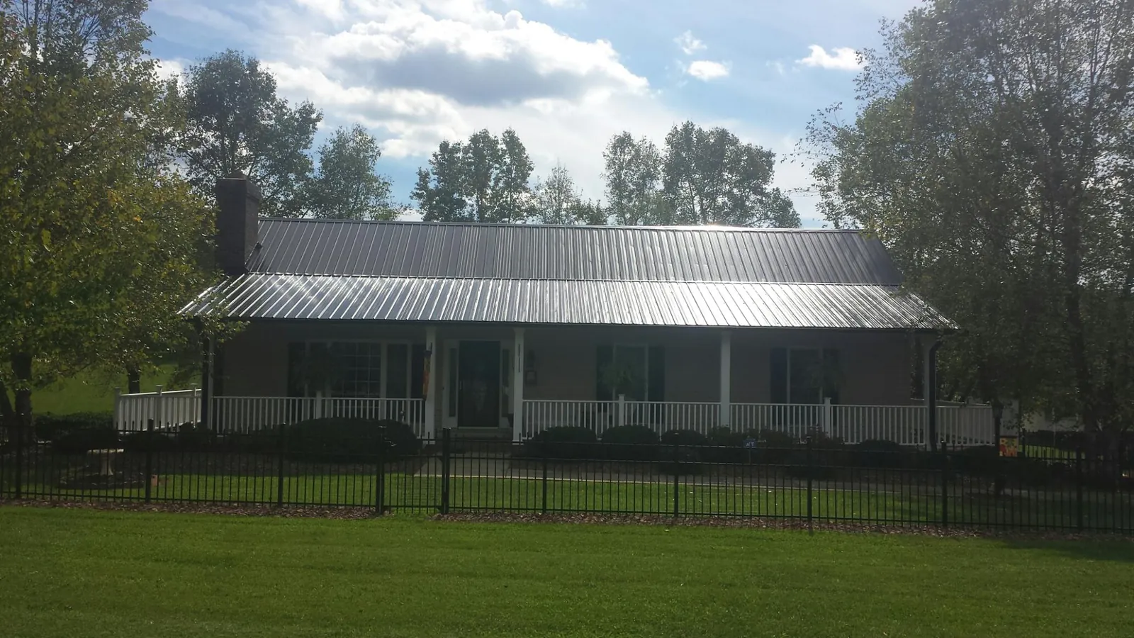 Gray metal roof on a brick ranch with a full width front porch — Gutter Guard Installation work by our crew in Harpswell