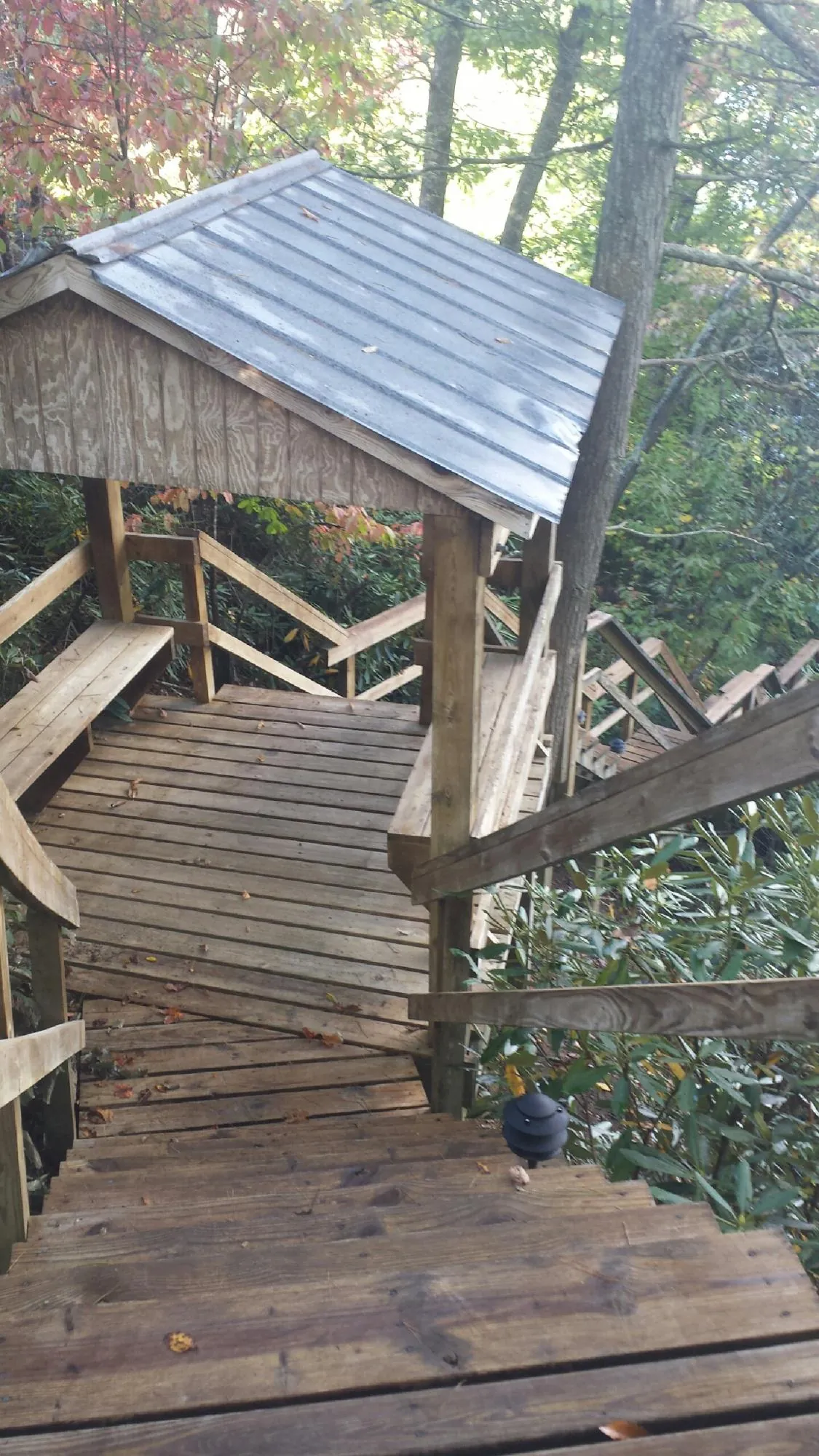 Metal roofed shelter over wooden steps on a wooded walkway — Skylight Repair & Installation work by our crew in Harpswell