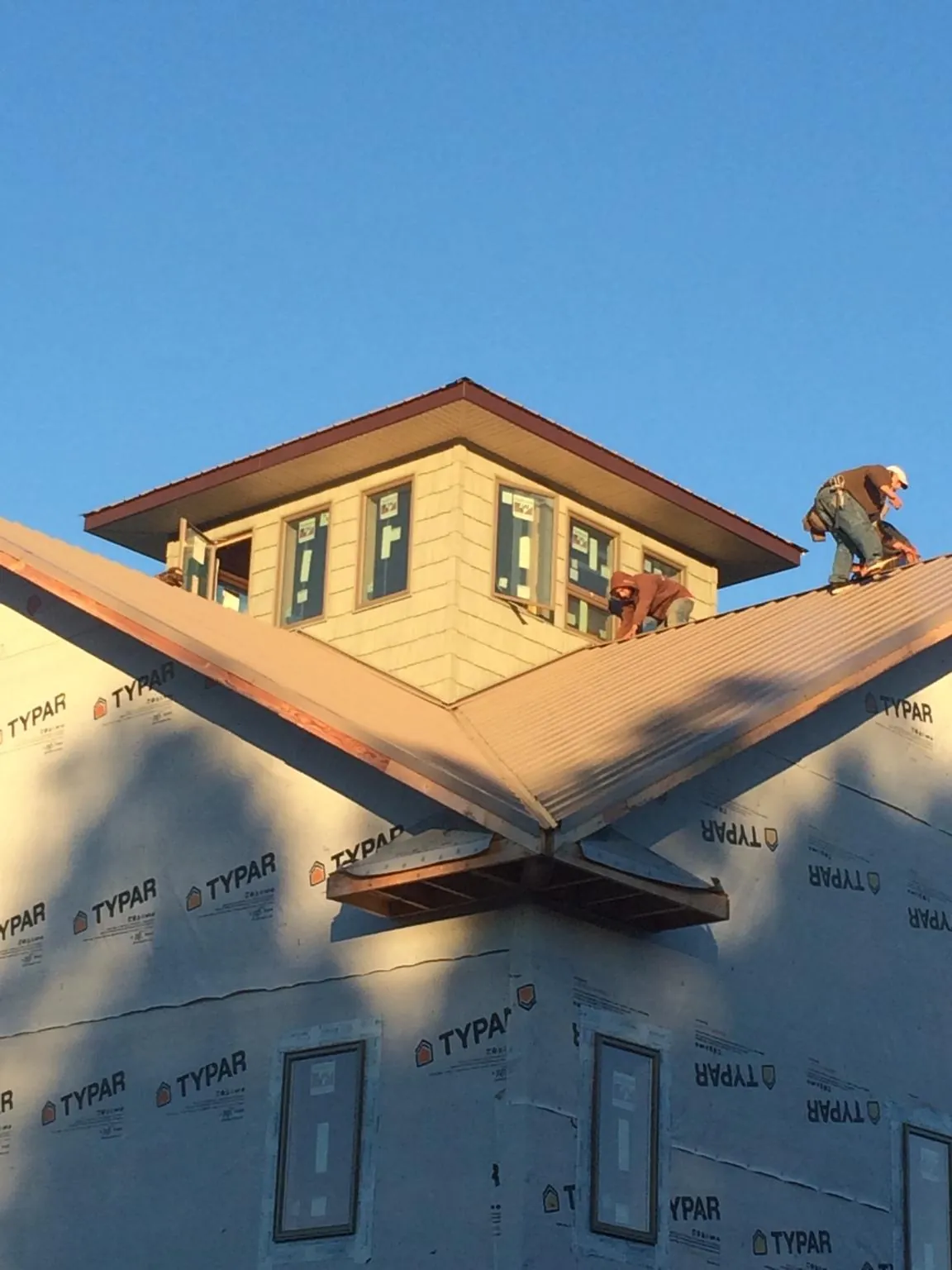 Roofers working around a rooftop cupola on a new metal roof at sunset — Roof Waterproofing in Harpswell by Roofing Brothers